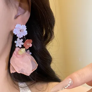 Primo piano dettagliato di eleganti orecchini a fiore in resina rosa e chiffon indossati