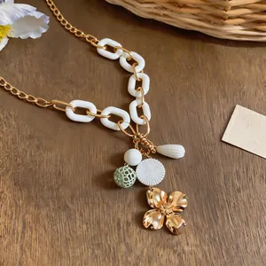 Detailed macro view of vintage gold chain necklace featuring floral and acrylic charms