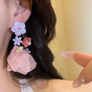 Dettaglio di orecchini pendenti a fiore in chiffon rosa con perno in argento puro