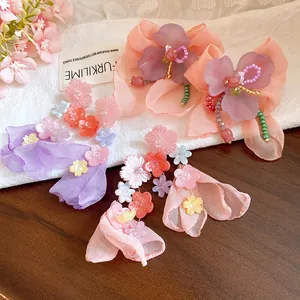 Dettaglio degli orecchini pendenti con fiori in resina e chiffon in uno stile dolce