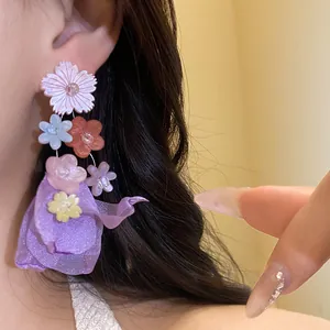 Primo piano della delicata trama degli orecchini pendenti con fiori in chiffon e resina