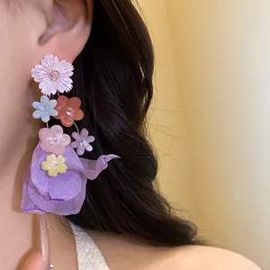 Dettaglio di eleganti orecchini con fiori in resina e chiffon viola indossati da una modella