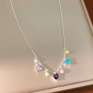 Sweet colorful heart-shaped zircon and pastel round bead necklace displayed on a beige jewelry tray