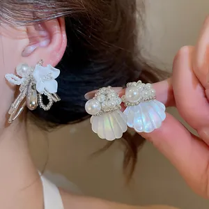 Close-up detail of elegant white flower pearl and iridescent shell stud earrings on ear