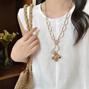 Detailed shot of a vintage flower pendant necklace with a toggle clasp on a model