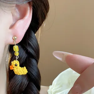Primo piano di un simpatico orecchino a forma di anatra di perline gialle su modella