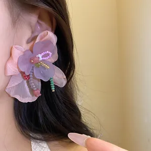 Vista dettagliata di eleganti orecchini a fiore in resina e chiffon indossati sull'orecchio.