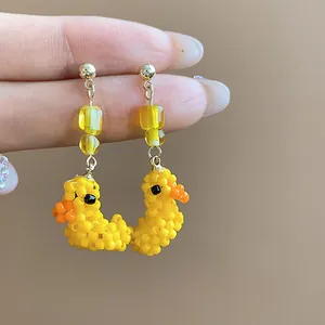 Dettaglio macro di orecchini a forma di anatra gialla fatti a mano con perle di vetro fini.