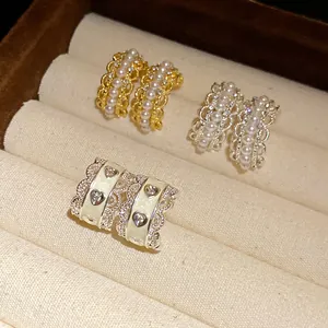 Detalle de pendientes de aro con perlas y encaje y tachuelas de esmalte de corazón