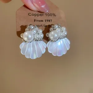 Detail showing iridescent shell-shaped earrings with multiple faux pearls