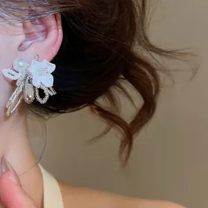 Detailed view of a white shell flower earring with pearls and silver accents