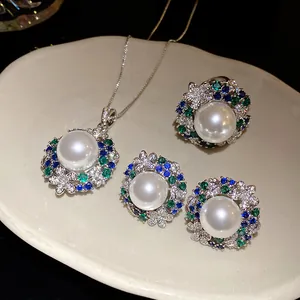 Vintage style jewelry set with white pearls and multicolored zircons on a tray.