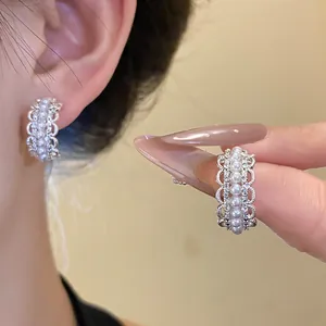 Primer plano de elegantes pendientes en forma de C con perlas finas y brillantes cristales.