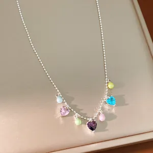 Close-up of dainty silver beaded necklace with colorful zircon hearts and pearls.