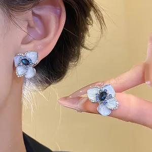 Primo piano di eleganti orecchini a fiore in smalto blu con strass scintillanti