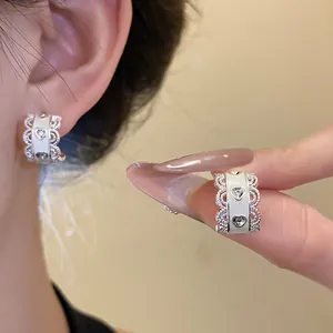 Primer plano de pendientes blancos en forma de C con corazones, encaje y piedras brillantes