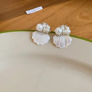 Macro detail view of French style pearl stud earrings with elegant white shell petals.