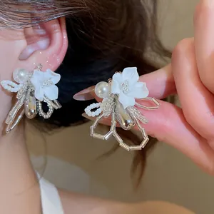 Detailed view of elegant French style white shell flower earrings with pearl accents