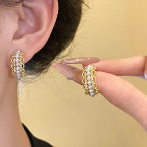 Vista detallada de pendientes en C con encaje, perlas y cristales en el modelo