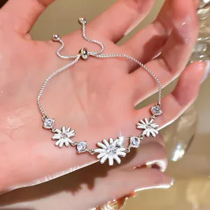 Vista detallada de pulsera de margaritas plateada con circonitas sobre un fondo cálido.