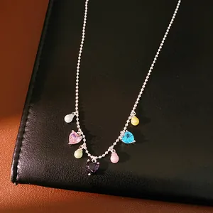 Close-up of colorful heart zircon and pearl necklace on a textured black surface