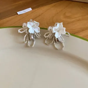 Macro view of elegant white flower earrings with pearls and bead details.