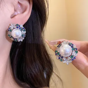 Detailed view of vintage 18k gold plated pearl earrings with blue and green zircons.