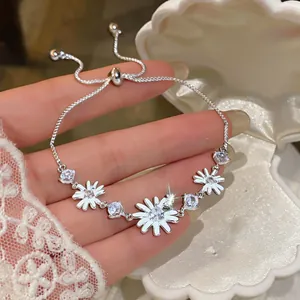 Vista detallada de una pulsera de margaritas de plata con circonitas en una caja de concha.