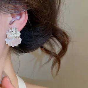 Close-up of French style pearl shell stud earring worn on ear, island vacation vibe