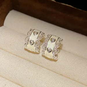 Primer plano de elegantes pendientes de aro en C con bordes de encaje y motivos corazón