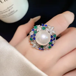 Detailed view of a vintage pearl ring featuring colorful zircons worn on a finger.