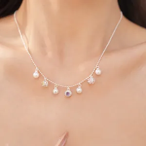 Close-up of a delicate silver necklace with pearls and colored zircons on a model