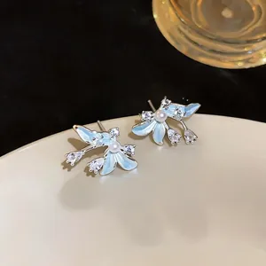 Vista detallada de pendientes florales de esmalte azul con perlas y circonitas brillo.