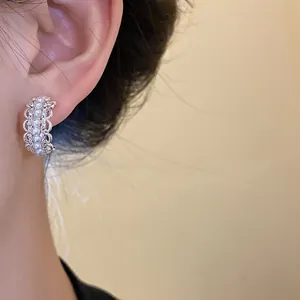 Vista detallada de pendientes plateados en forma de C con perlas y strass finos