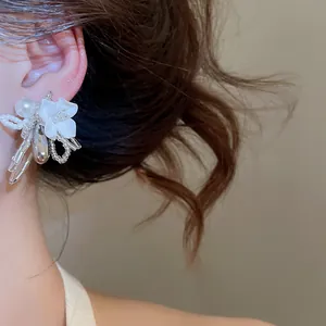 Close-up of white shell flower stud earring with pearl and bead detail