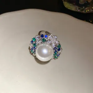 Elegant vintage pearl ring with blue and green zircons on a white ceramic plate