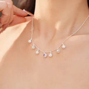 Close-up detail of silver ball chain necklace featuring white pearls and purple zircon charms