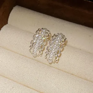 Primer plano de pendientes de perlas en forma de C con bordes de encaje y circonitas