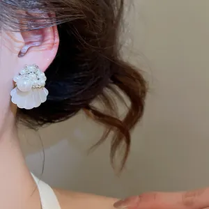 Close-up of elegant French pearl and shell earrings worn on model's ear