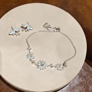 Vista detallada del conjunto de pendientes y pulsera de margarita de plata con circonitas