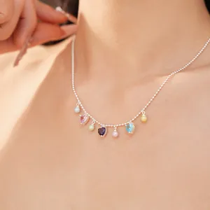 Detailed shot of a colorful heart zircon and pearl bead necklace on a woman's neck