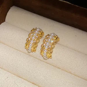 Vista detallada de elegantes pendientes en forma de C dorados con perlas y cristales.