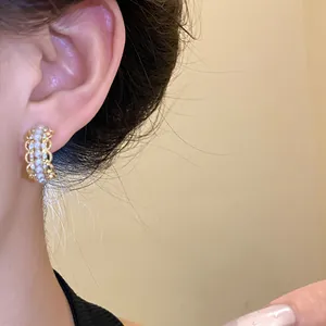 Detalle de pendientes en forma de C con diseño de encaje, perlas y cristales brillantes.