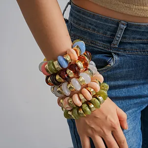 Close-up of stacked colorful acrylic geometric beaded elastic bracelets on wrist