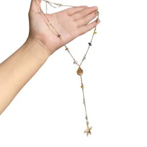 Bohemian stone beaded Y-necklace with gold shell and starfish charms held in hand