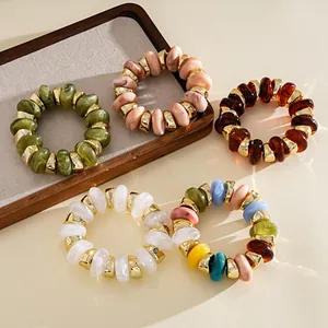Detailed view of colorful acrylic geometric beaded stretch bracelets with gold accents