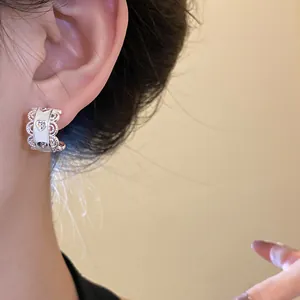 Primer plano detallado de pendientes plateados en forma de C con diseño de corazón