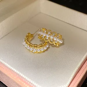 Vista detallada de elegantes pendientes en forma de C dorados con perlas y strass