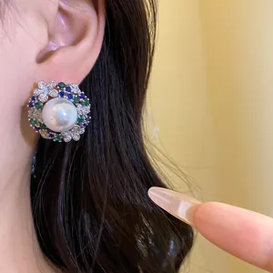 Close-up of a vintage-style earring with a large pearl, blue zircons, and floral accents.