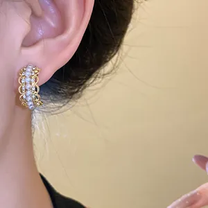 Primer plano de pendientes de encaje en forma de C con perlas y diamantes